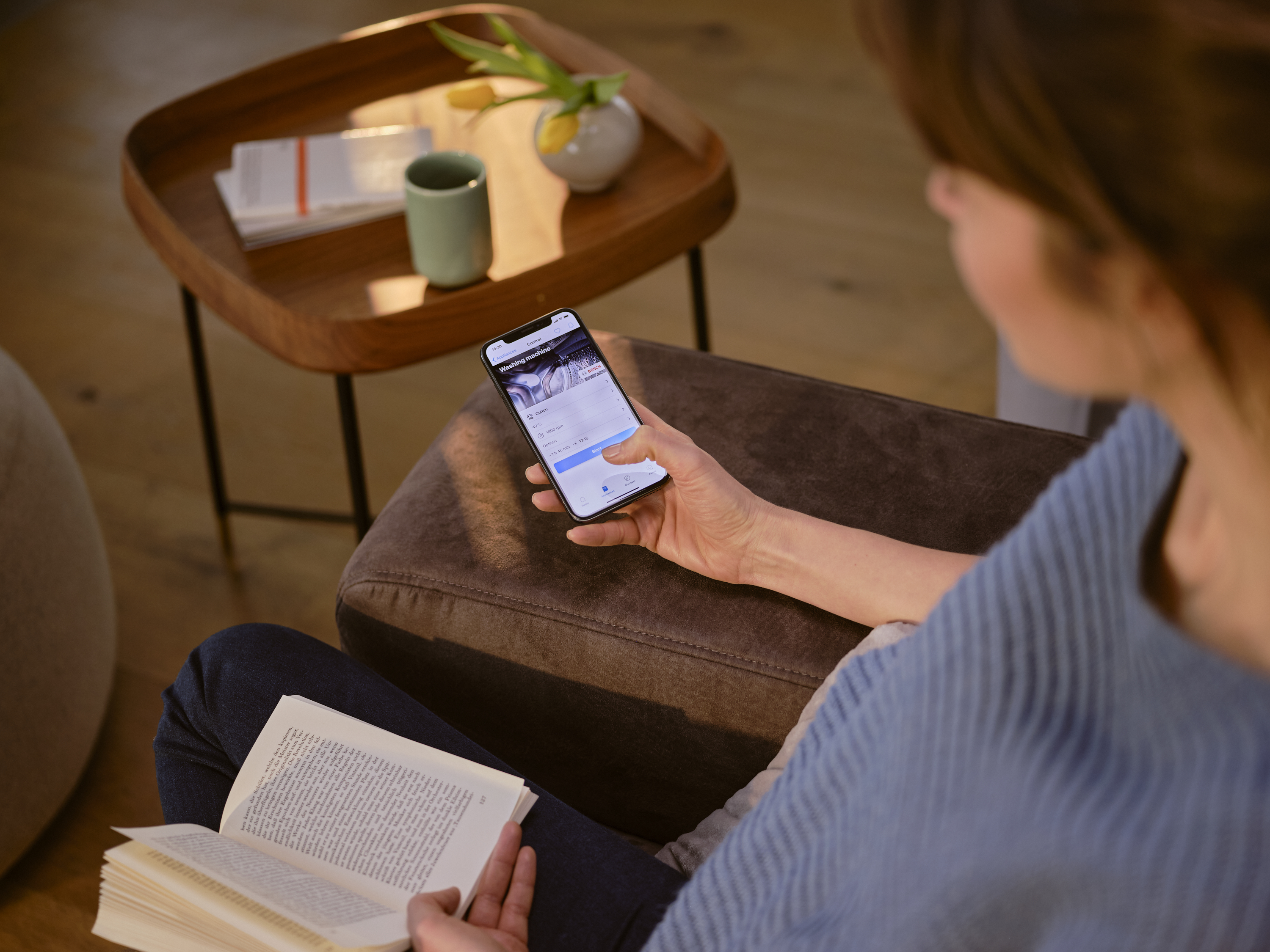 person on smartphone with book in other hand