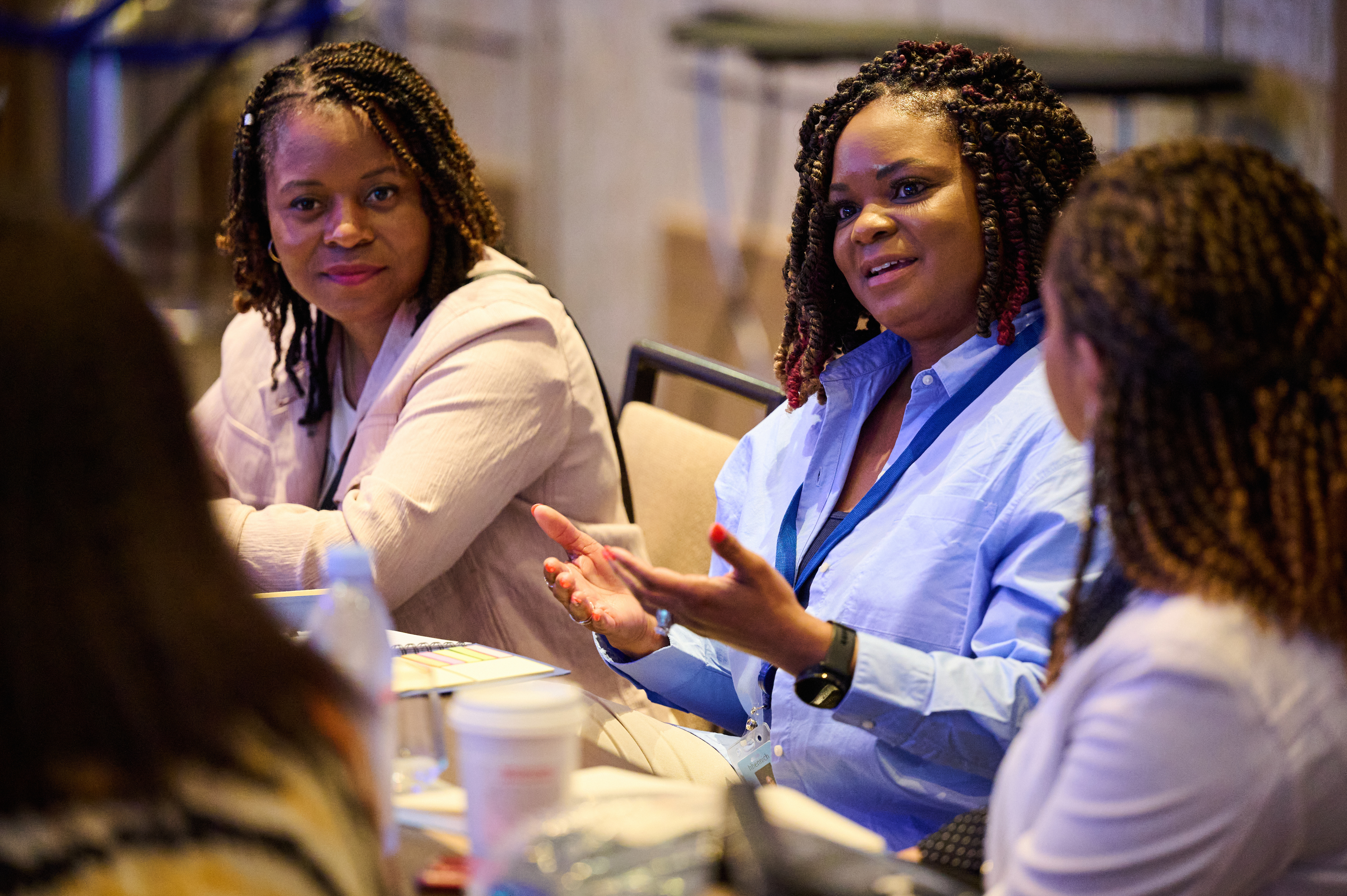 A group of women engaged in a discussion around a conference table during a professional meeting or event.