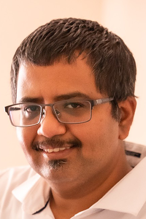 Portrait headshot of an individual in glasses and a white shirt
