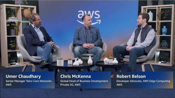 Three individuals seated in a studio setting with an AWS logo in the background, accompanied by name and title captions for Umer Chaudhary, Chris McKenna, and Robert Belson.