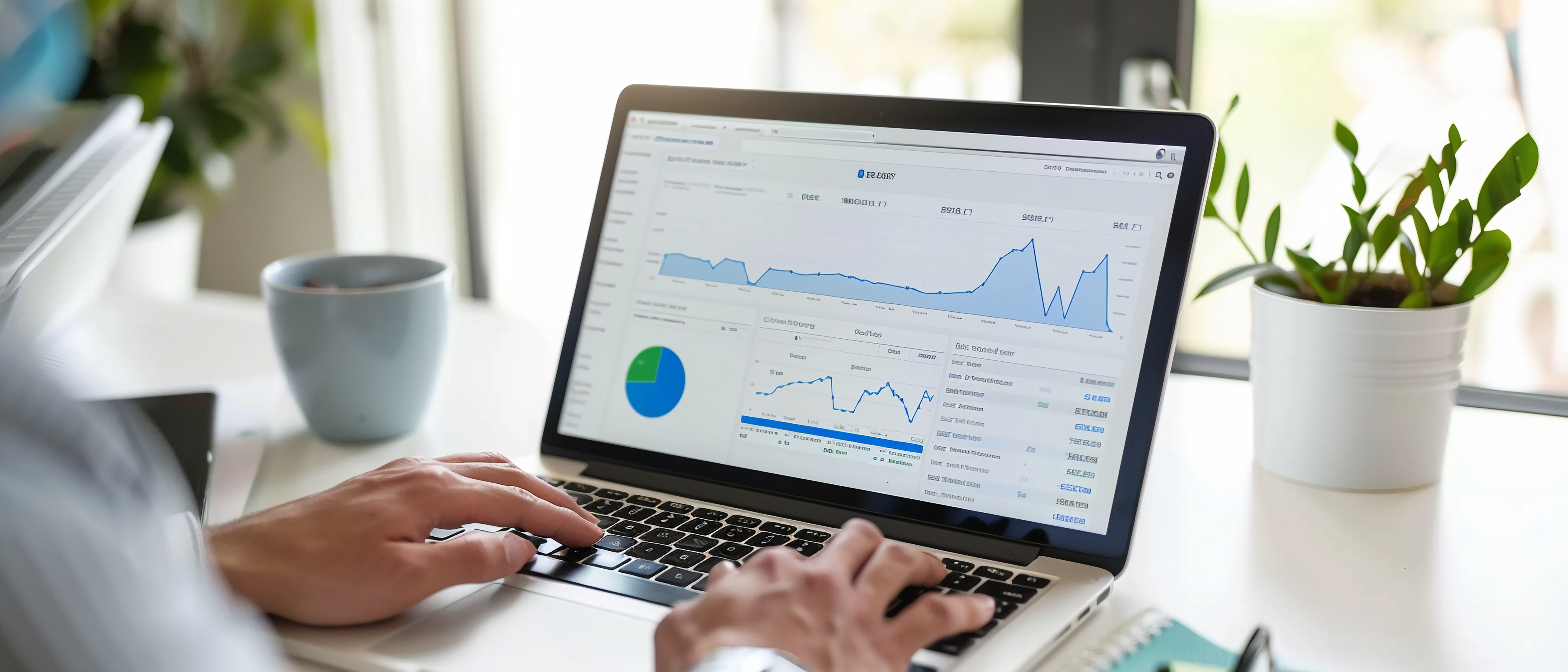 A person using a laptop displaying a CRM customer behavior analysis dashboard with data charts and graphs, set on a desk with a coffee mug and a potted plant.