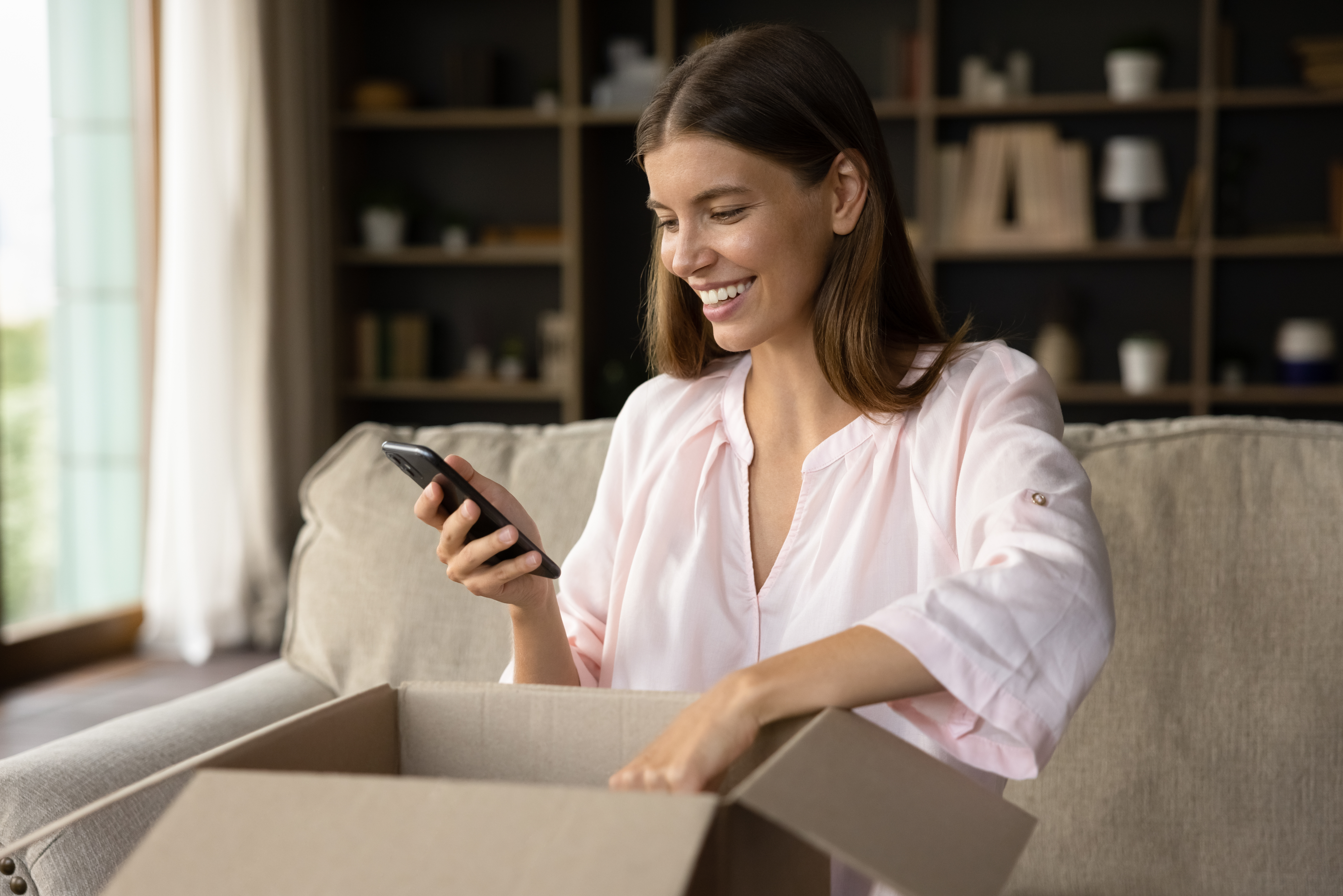 Happy woman unbox parcel box, check ordered items in phone use retail ecommerce application, leave positive feedback to customer, feel satisfied with delivered goods, quick delivery services concept