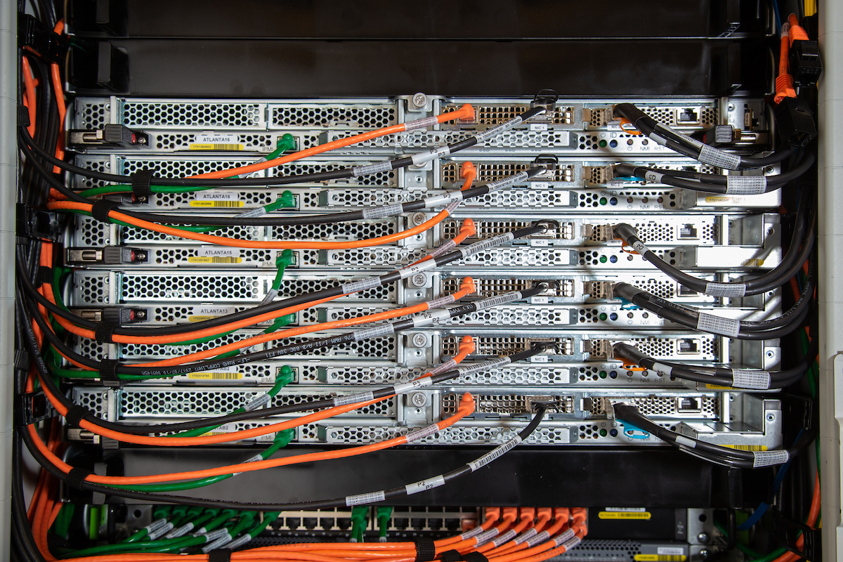 Close-up of a server rack with multiple interconnected servers and colorful cables, including orange and green wires.