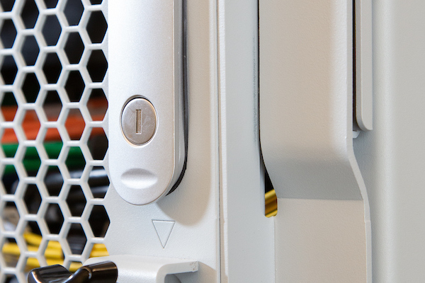 Close-up of a server cabinet lock with a hexagonal mesh pattern and visible cables in the background.
