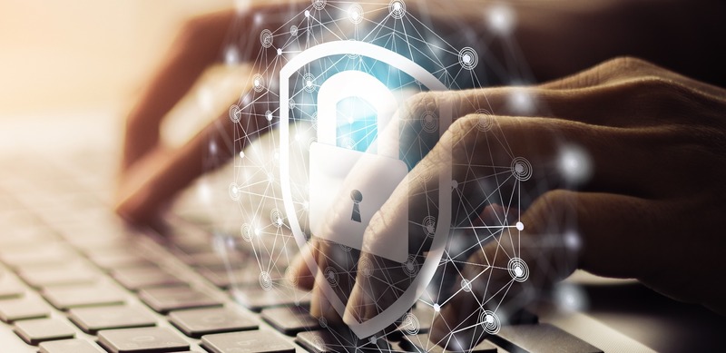 A conceptual illustration showing hands typing on a keyboard with a digital lock and shield overlay, representing cybersecurity and data protection.