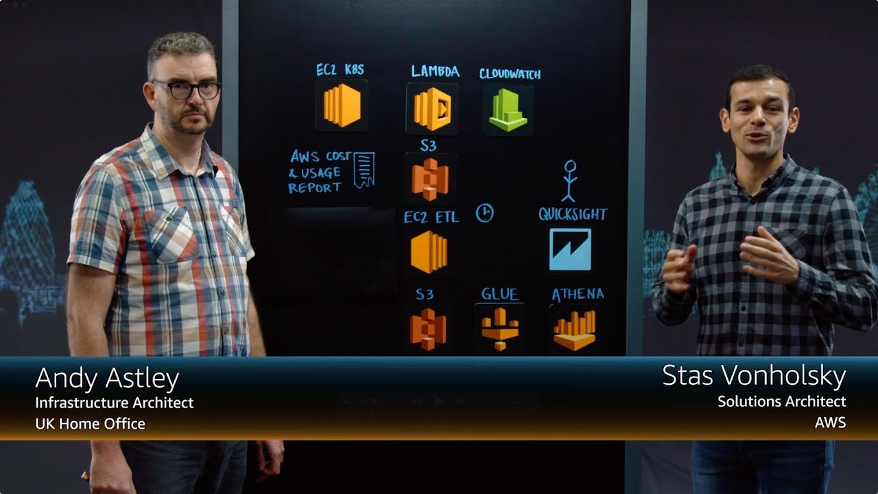 YouTube thumbnail image for an AWS architecture presentation featuring Andy Astley, Infrastructure Architect at UK Home Office, and Stas Vonholsky, Solutions Architect at AWS. The image shows both presenters standing on either side of a digital board displaying AWS services and architecture icons.