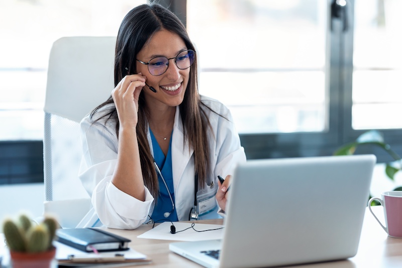 Shot of female doctor talking with colleagues through a video call with a laptop in the consultation.