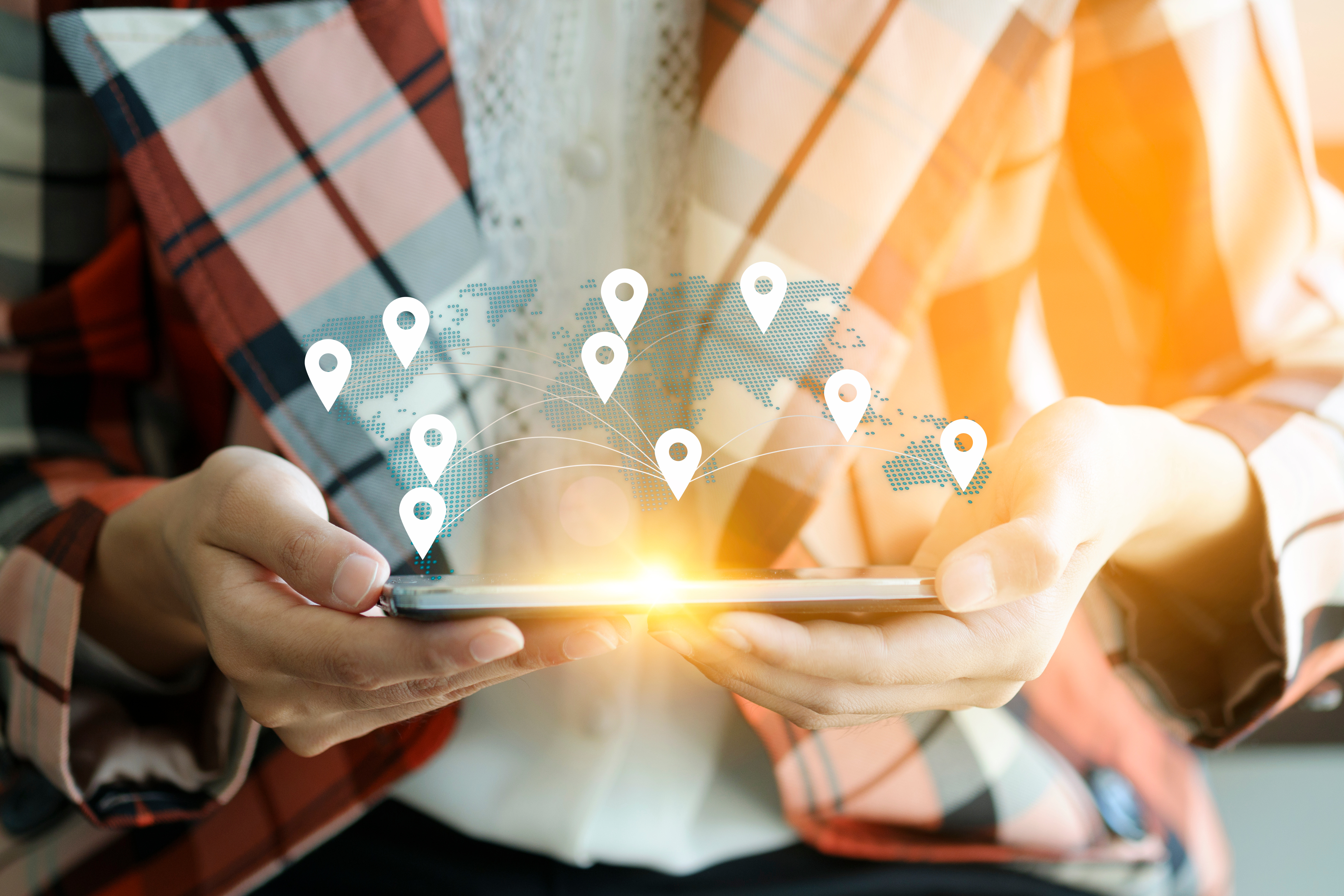 A person holding a tablet with a digital world map overlay and location markers, representing global business, online shipping, and international logistics.