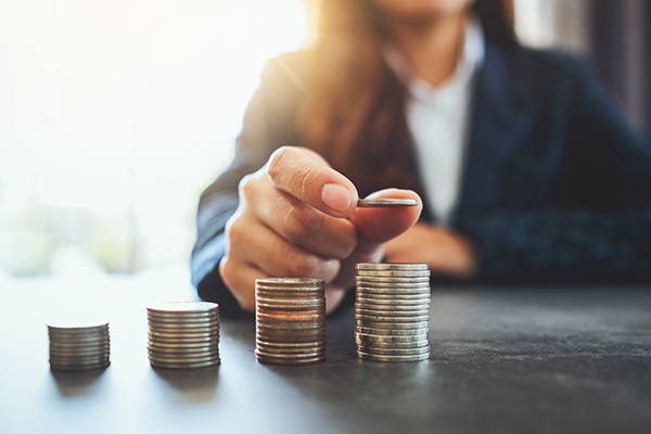 Businesswoman holding and stacking coins on the table