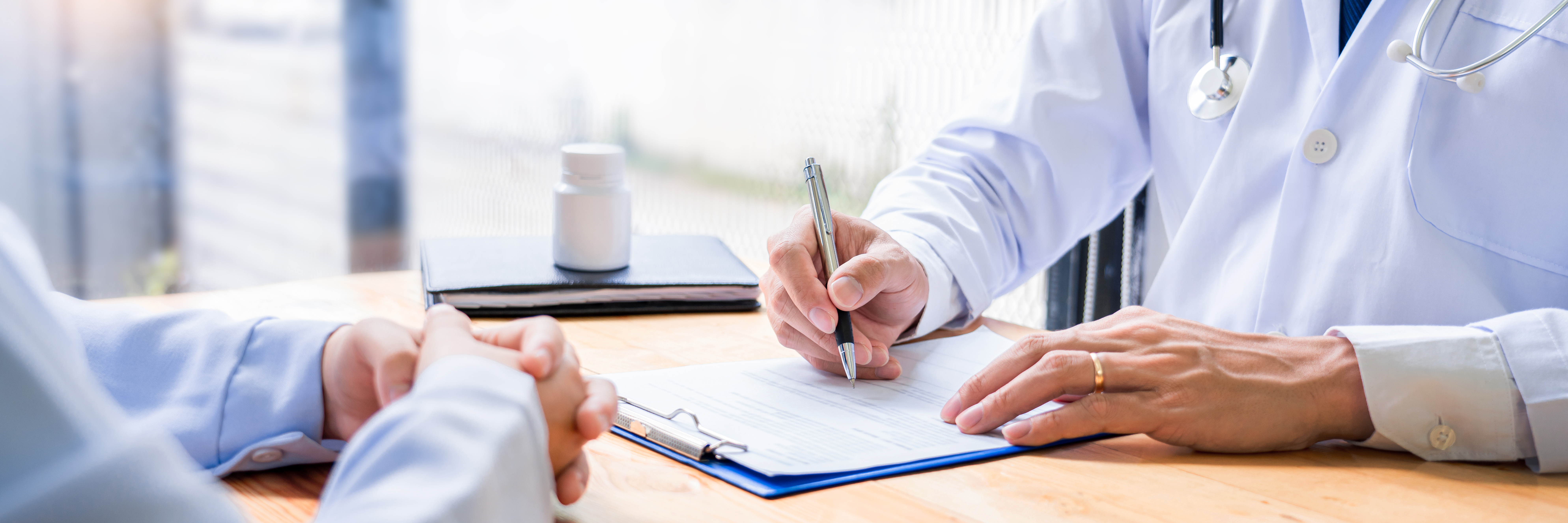 Charming Asian male doctor giving advice and medical informations and diagnosis to a female patient at consulting room in clinic