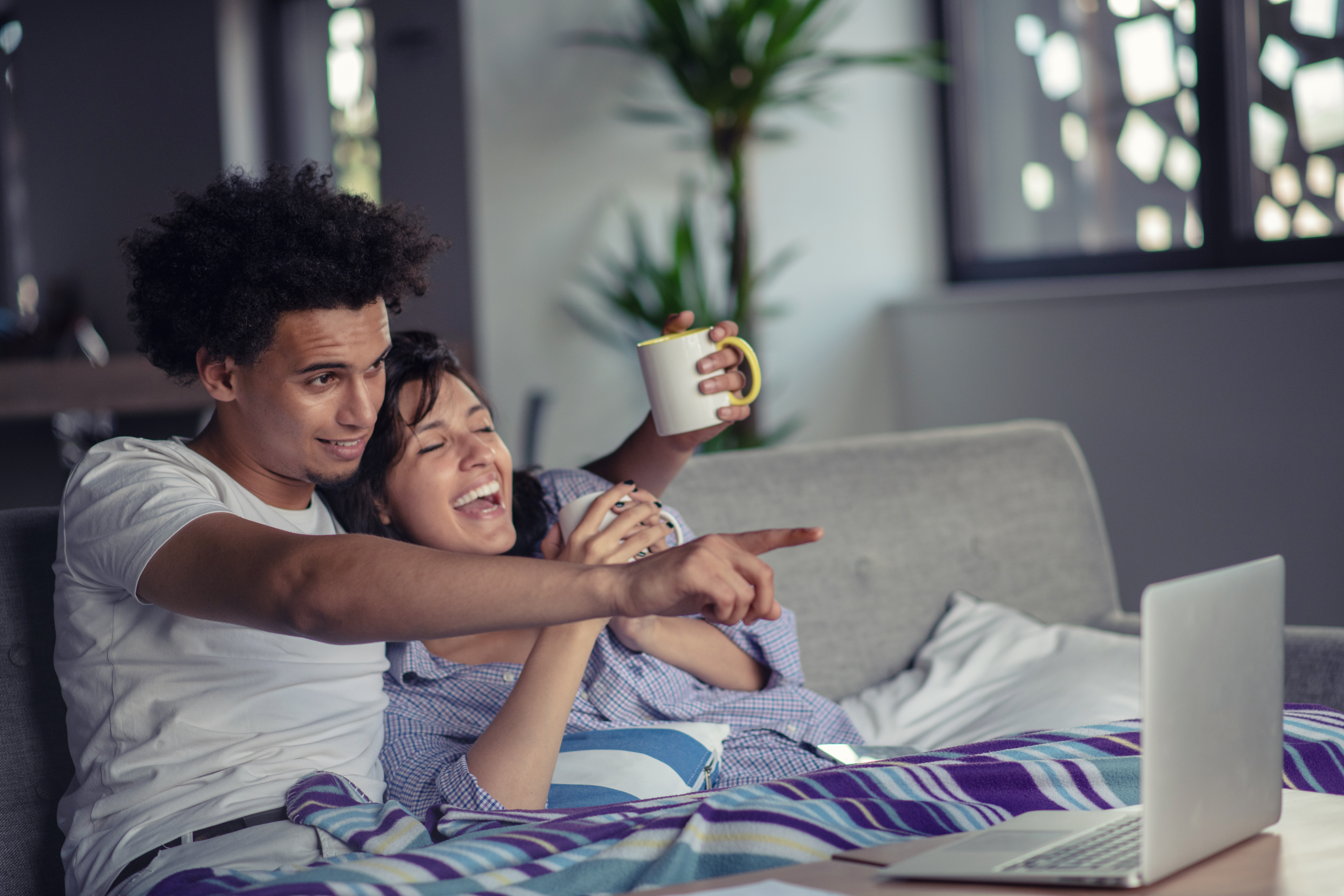 Young couple watching a movie on their laptop in bed.