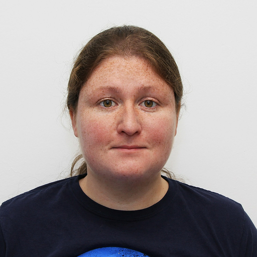 Portrait of a person with light skin, brown hair, and freckles, wearing a dark t-shirt, against a plain white background.
