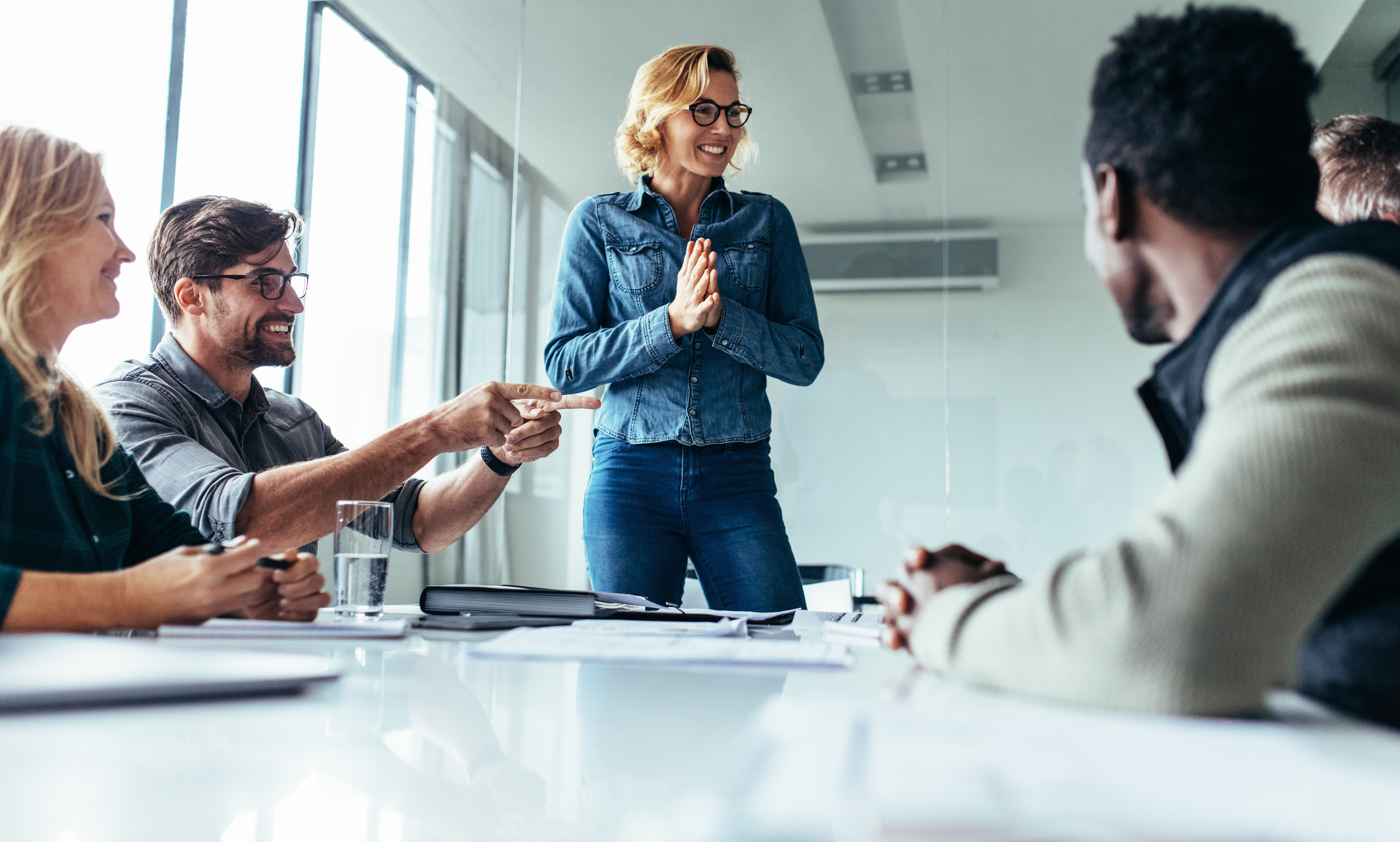 Young happy woman presenting her idea to colleagues in meeting. Businesspeople discussing about new project.