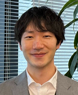 Portrait of Miyazaki Kouichi, speaker for Toda Kensetsu case study, wearing a suit and standing in an office setting with plants and window blinds in the background.