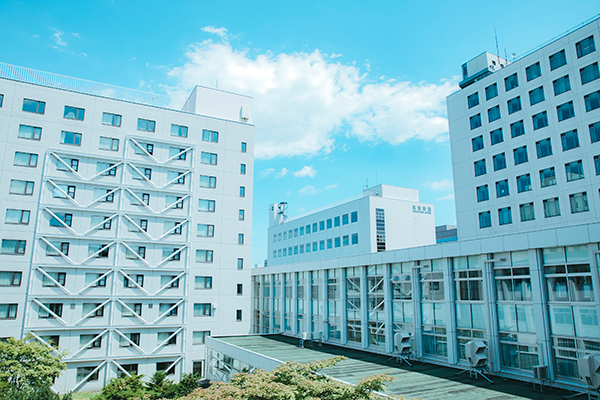 Modern Japanese university campus buildings with large windows and geometric architecture under a clear blue sky.