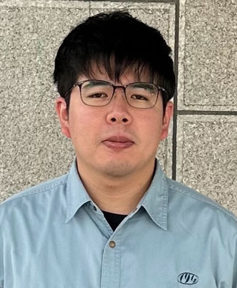 Portrait of a case study speaker wearing glasses and a button-up shirt in front of a stone wall.