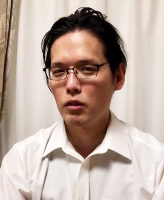 Portrait of a case study speaker in a white shirt and glasses, set against a neutral indoor background. Used for Ikuyo case study materials.