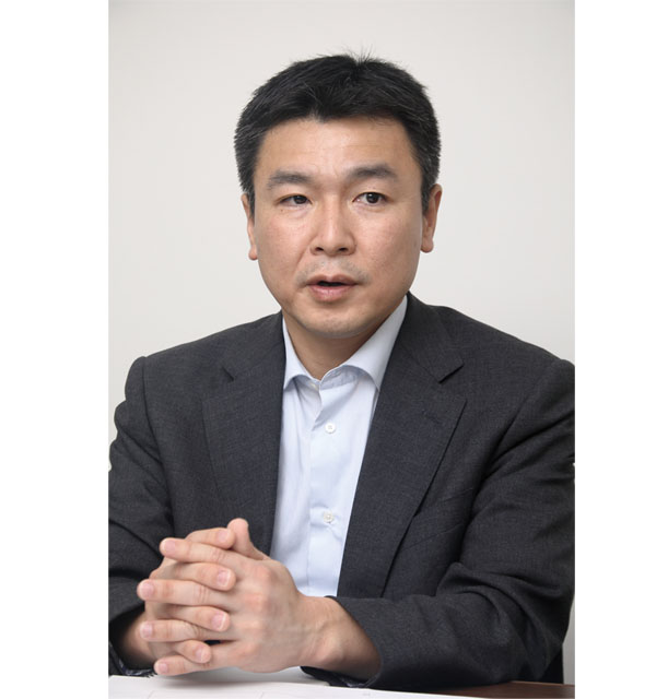 Portrait of a businessman in a suit, seated at a desk, part of the Dainichiseika solution case studies for AWS Japan.