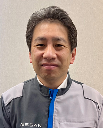 Portrait of a Nissan employee wearing a company uniform, standing in front of a plain background.