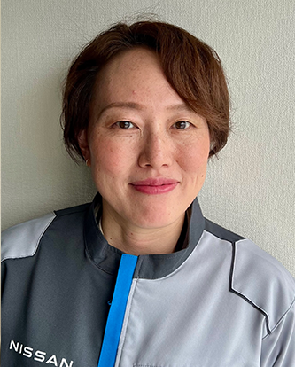 Portrait of a Nissan employee in a gray and blue company uniform, standing against a light background.