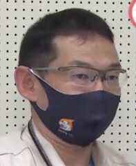 A man wearing glasses and a dark face mask in front of a white perforated background. The setting appears to be in Hamamatsu.